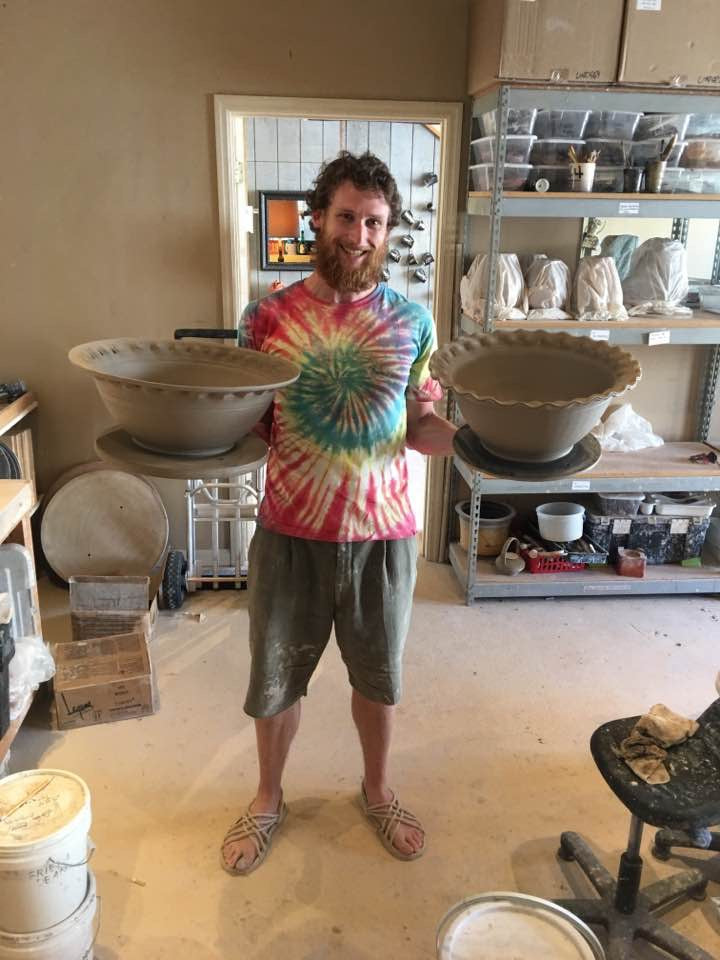 Harrison Hickman holding two handmade bowls in the pottery studio